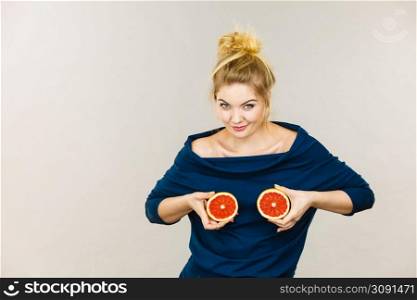 Healthy diet, refreshing food full of vitamins. Happy crazy woman holding sweet delicious citrus fruit, red grapefruit on breast. Woman holding red grapefruit on breast