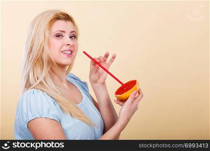 Healthy diet, refreshing food full of vitamins. Woman drinking juice from juicy fruit, red grapefruit. Woman drinking juice from fruit, red grapefruit