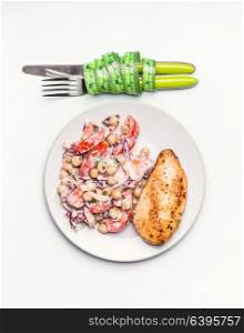 Healthy dieting meal . Chickpeas salad and grilled chicken breast with cutlery and measuring tape on white background, top view