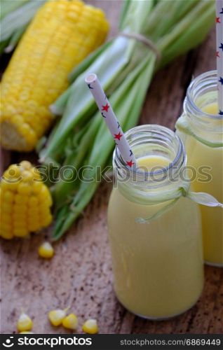 Healthy drinking for breakfast from sweetcorn, corn milk jar in yellow, rich vitamin, tasty, nutrition from maize, fresh milk bottle on wooden background