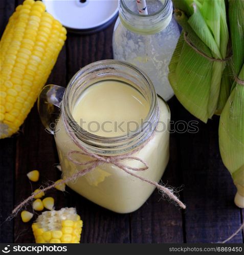 Healthy drinking for breakfast from sweetcorn, corn milk jar in yellow, rich vitamin, tasty, nutrition from maize, fresh milk bottle on wooden background