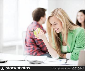 healthy eating and education concept - picture of smiling student girl eating apple at school