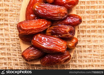 Healthy eating. Closeup dried dates on wooden spoon table sackcloth rustic background