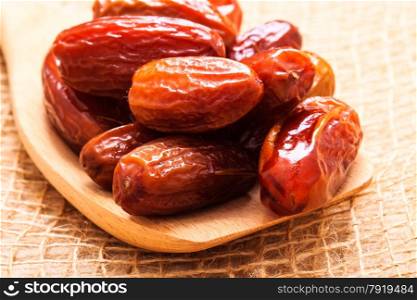 Healthy eating. Closeup dried dates on wooden spoon table sackcloth rustic background