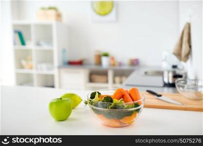 healthy eating, cooking and food concept - vegetables and fruits on kitchen table at home. bowl with food on kitchen table at home