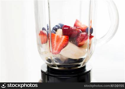 healthy eating, cooking, kitchen appliances and technology concept - close up of blender shaker with fruits and berries