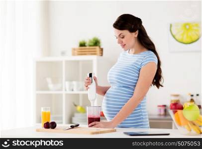 healthy eating, cooking, pregnancy and people concept - pregnant woman with blender preparing fruit smoothie drink at home kitchen. pregnant woman with blender cooking fruits at home