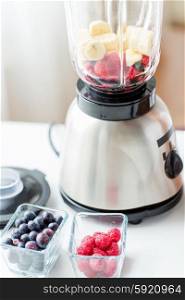 healthy eating, cooking, vegetarian food and diet concept - close up of blender with berries and fruits on table
