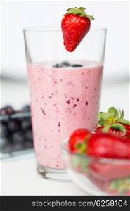 healthy eating, cooking, vegetarian food and dieting concept - close up of milkshake decorated with strawberry and berries