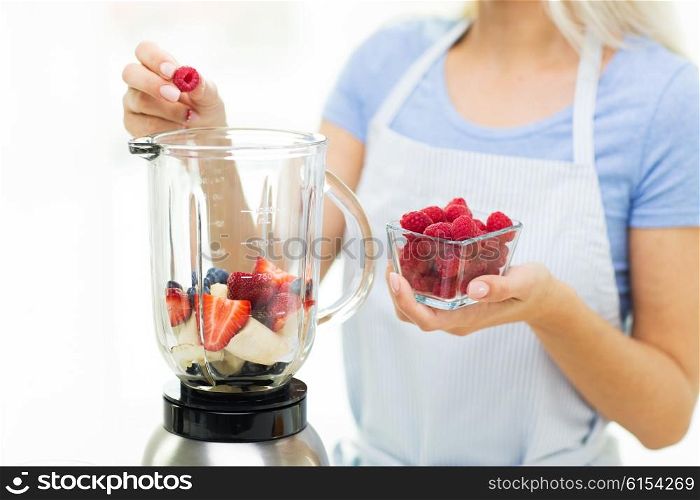 healthy eating, cooking, vegetarian food, diet and people concept - close up of woman with blender making fruit shake at home