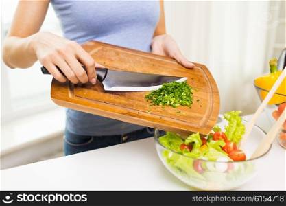 healthy eating, cooking, vegetarian food, diet and people concept - close up of woman adding chopped green onion to salad