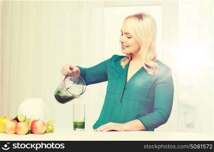 healthy eating, cooking, vegetarian food, diet and people concept - smiling young woman with blender shaker jug pouring green vegetable smoothie or juice into glass at home kitchen. happy woman with blender jug pouring juice at home