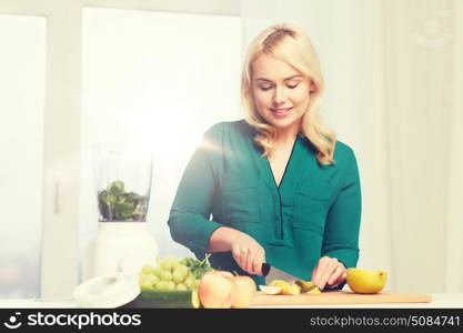 healthy eating, cooking, vegetarian food, diet and people concept - smiling young woman with blender and knife chopping fruits and vegetables on cutting board at home. smiling woman with blender cooking food at home. smiling woman with blender cooking food at home