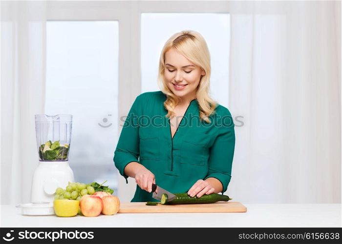 healthy eating, cooking, vegetarian food, diet and people concept - smiling young woman with blender and knife chopping fruits and vegetables on cutting board at home
