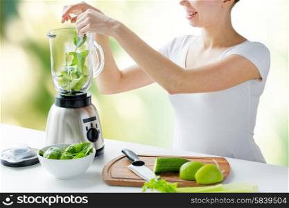 healthy eating, cooking, vegetarian food, dieting and people concept - close up of young woman with blender and green vegetables making detox shake or smoothie over natural background