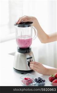 healthy eating, cooking, vegetarian food, dieting and people concept - close up of woman hands blending fruit shake in blender at home