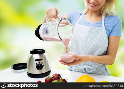 healthy eating, cooking, vegetarian food, dieting and people concept - close up of young woman pouring fruit shake from blender shaker jug to glass over green natural background