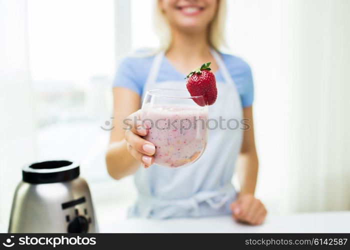 healthy eating, cooking, vegetarian food, dieting and people concept - close up of woman holding glass of fruit strawberry shake at home