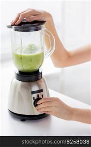 healthy eating, cooking, vegetarian food, dieting and people concept - close up of woman hands with blender making detox shake shake or smoothie at home