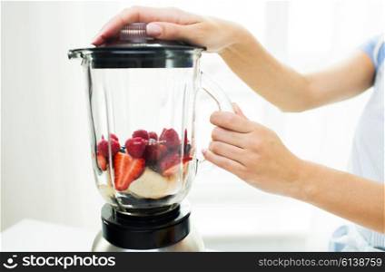 healthy eating, cooking, vegetarian food, dieting and people concept -close up of woman with blender making fruit shake r at home