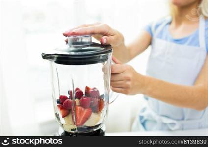 healthy eating, cooking, vegetarian food, dieting and people concept -close up of woman with blender making fruit shake r at home