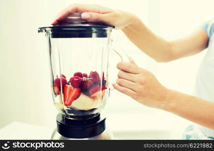 healthy eating, cooking, vegetarian food, dieting and people concept -close up of woman with blender making fruit shake r at home