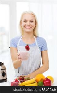 healthy eating, cooking, vegetarian food, dieting and people concept - smiling woman holding glass of fruit shake at home