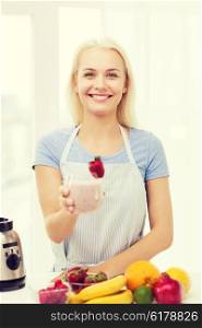 healthy eating, cooking, vegetarian food, dieting and people concept - smiling woman holding glass of fruit shake at home