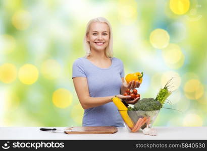 healthy eating, cooking, vegetarian food, dieting and people concept - smiling young woman with bowl of vegetables over green lights background