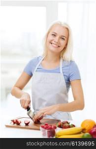 healthy eating, cooking, vegetarian food, dieting and people concept - smiling young woman chopping fruits and berries at home
