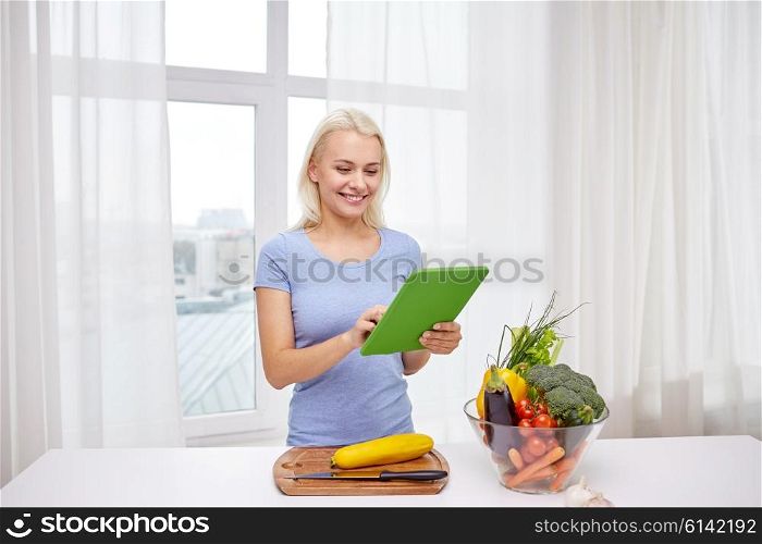 healthy eating, cooking, vegetarian food, technology and people concept - smiling young woman with tablet pc computer and bowl of vegetables at home