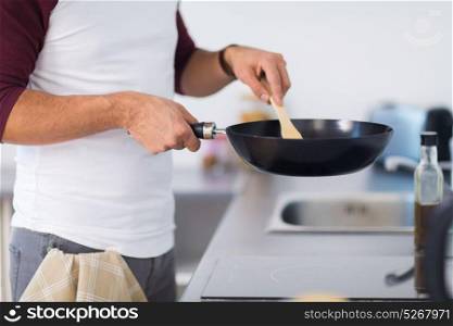 healthy eating, culinary and people concept - close up of man with frying pan cooking food at home kitchen. man with frying pan cooking food at home kitchen