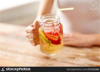 healthy eating, detox and people concept - close up of woman holding mason jar glass with fruit water at home. close up of woman holding glass with fruit water