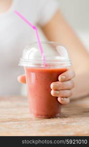 healthy eating, diet and people concept - close up of woman holding plastic cup with juice or smoothie