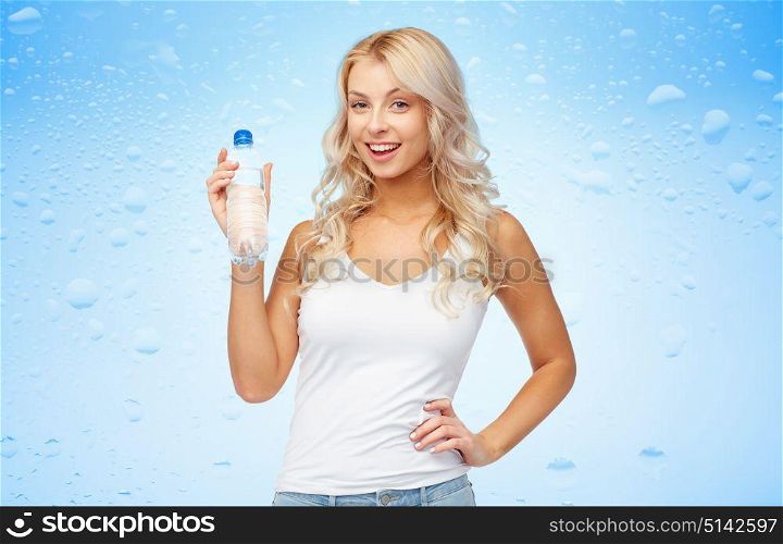 healthy eating, diet and people concept - happy beautiful young woman holding bottle of water over wet blue background. happy beautiful young woman with bottle of water