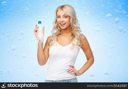 healthy eating, diet and people concept - happy beautiful young woman holding bottle of water over wet blue background. happy beautiful young woman with bottle of water