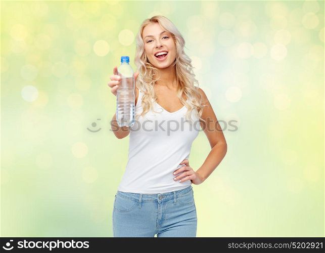 healthy eating, diet and people concept - happy beautiful young woman holding bottle of water over summer green lights background. happy beautiful young woman with bottle of water