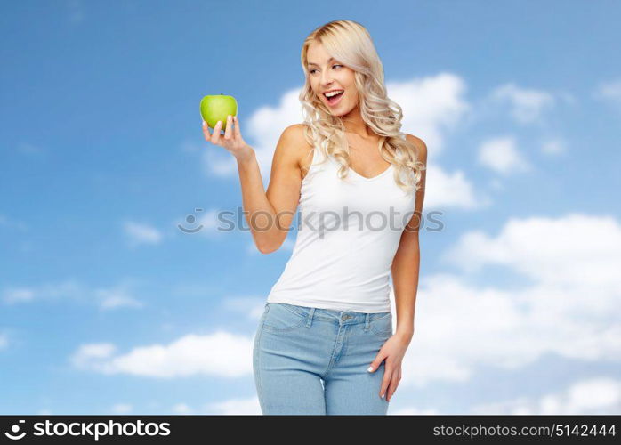 healthy eating, diet and people concept - happy beautiful young woman with green apple over blue sky and clouds background. happy young woman with green apple over blue sky