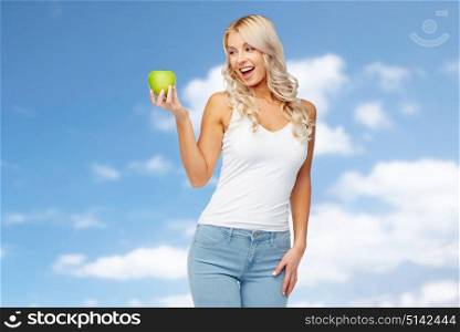 healthy eating, diet and people concept - happy beautiful young woman with green apple over blue sky and clouds background. happy young woman with green apple over blue sky