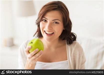 healthy eating, diet and people concept - smiling young woman with green apple at home