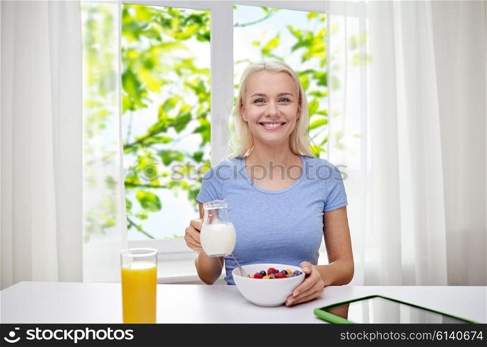 healthy eating, diet, lifestyle and people concept - smiling young woman with milk and cornflakes having breakfast over green natural background