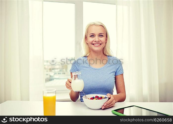 healthy eating, diet, lifestyle and people concept - smiling young woman with milk and cornflakes having breakfast at home