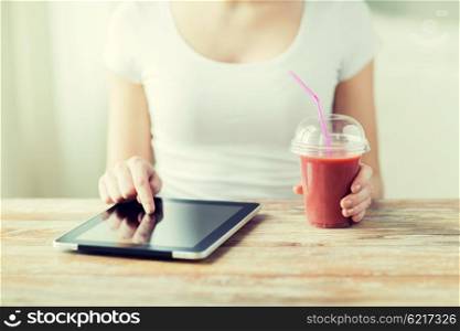 healthy eating, diet, technology and people concept - close up of woman hands with tablet pc computer and cup of smoothie sitting at table