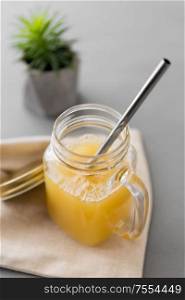 healthy eating, dieting and eco friendly concept - glass mug of fruit juice and reusable metallic straw. glass mug of juice and reusable metallic straw