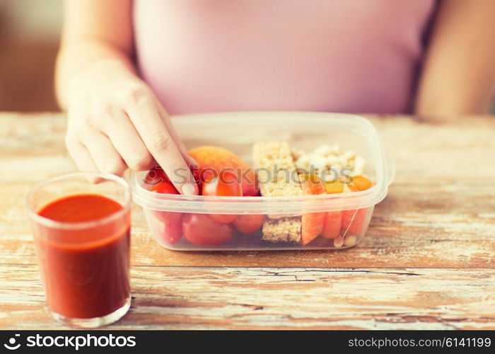 healthy eating, dieting and people concept - close up of woman hands with food in plastic container and fresh tomato juice at home kitchen