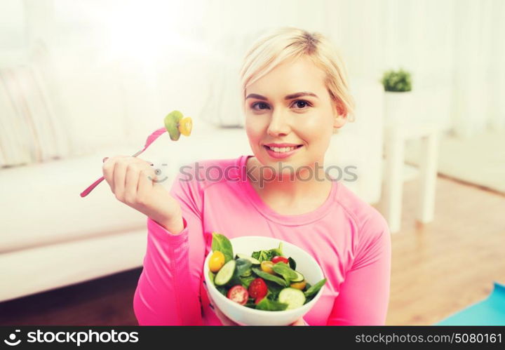healthy eating, dieting and people concept - smiling young woman eating vegetable salad at home. smiling young woman eating salad at home