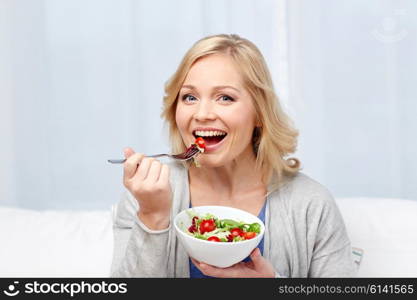 healthy eating, dieting and people concept - smiling young woman eating vegetable salad at home