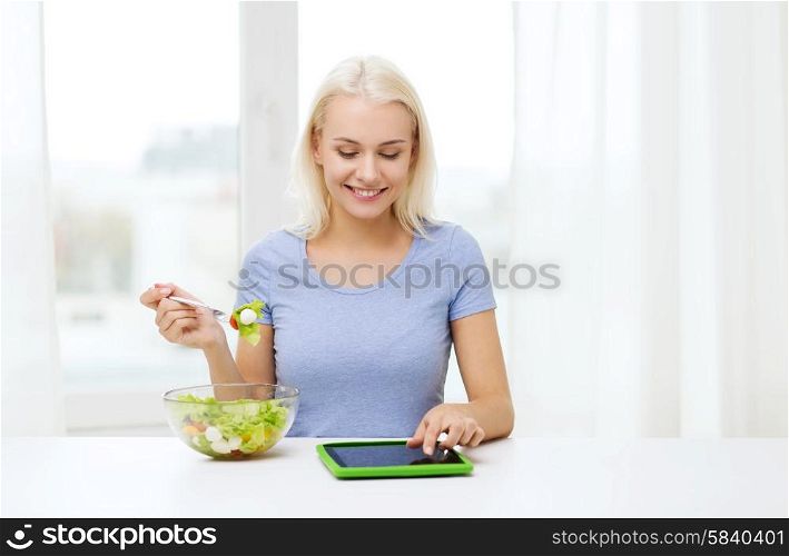 healthy eating, dieting and people concept - smiling young woman with tablet pc computer eating vegetable salad at home