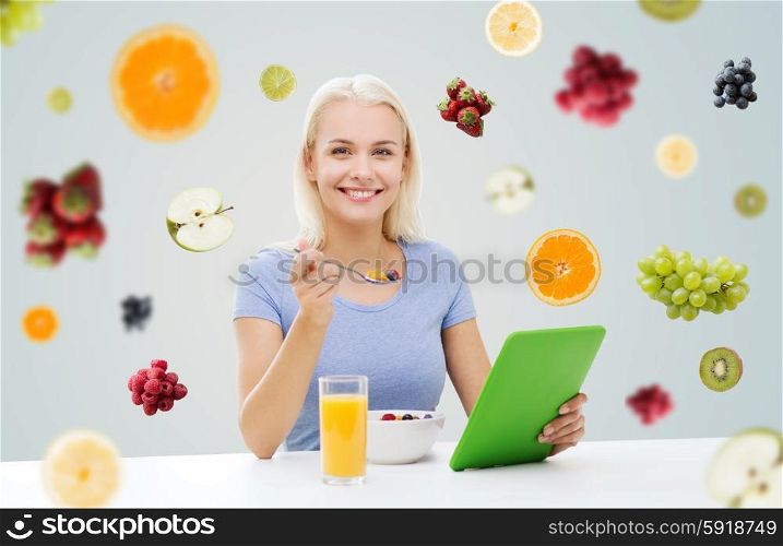 healthy eating, dieting and people concept - smiling young woman with tablet pc computer eating breakfast over fruits and berries on gray background