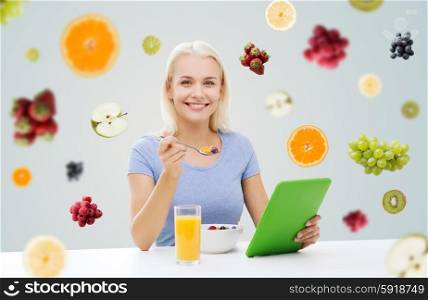 healthy eating, dieting and people concept - smiling young woman with tablet pc computer eating breakfast over fruits and berries on gray background